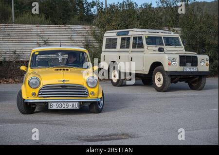 Vorderansicht eines klassischen gelben Morris Mini Cooper S 1300 und eines Land Rover Santana Series III Stockfoto