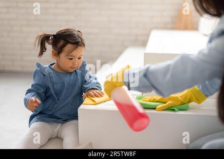 Asiatische Mami Und Baby-Tochter-Reinigung Mit Reinigungsmittel Zu Hause Stockfoto