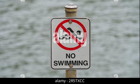 Nahaufnahme eines Hinweisschilds zum Schwimmen neben einem Gewässer Stockfoto