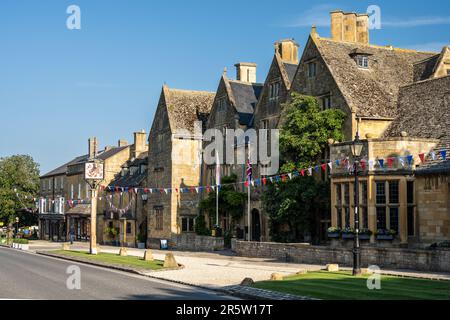 Das Lygon Arms, ein Gasthaus aus dem 17. Jahrhundert, und andere malerische alte Cotswold-Steingebäude sind während eines Sommerfestes in der mit Flöten dekoriert Stockfoto