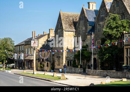 Das Lygon Arms, ein Gasthaus aus dem 17. Jahrhundert, und andere malerische alte Cotswold-Steingebäude sind während eines Sommerfestes in der mit Flöten dekoriert Stockfoto