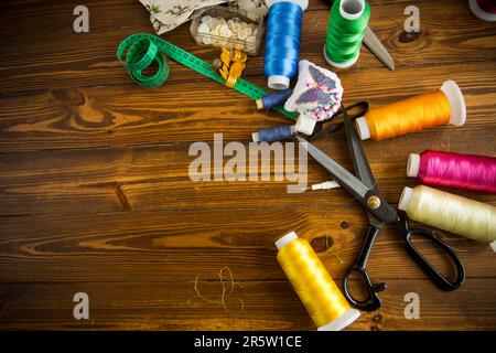 Ein Satz Werkzeuge und Fäden zum Nähen von Kleidung auf Holzhintergrund. Stockfoto