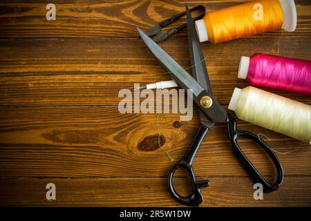 Ein Satz Werkzeuge und Fäden zum Nähen von Kleidung auf Holzhintergrund. Stockfoto
