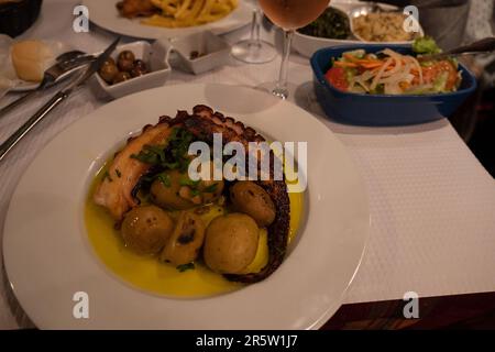 Gegrillter Tintenfisch mit gebackenen Kartoffeln und Olivenöl im Weißflugzeug im Restaurant serviert Stockfoto