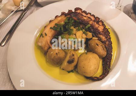 Gegrillter Tintenfisch mit gebackenen Kartoffeln und Olivenöl im Weißflugzeug im Restaurant serviert Stockfoto