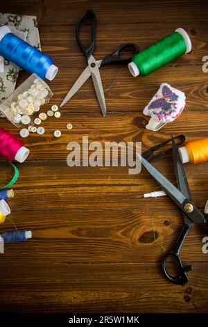 Ein Satz Werkzeuge und Fäden zum Nähen von Kleidung auf Holzhintergrund. Stockfoto
