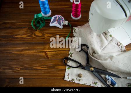 Ein Satz Werkzeuge und Fäden zum Nähen von Kleidung auf Holzhintergrund. Stockfoto