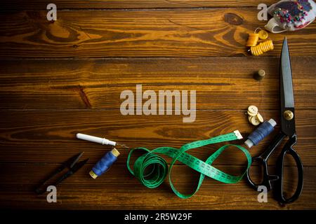 Ein Satz Werkzeuge und Fäden zum Nähen von Kleidung auf Holzhintergrund. Stockfoto