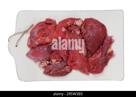 Fleischstücke auf einem Keramikbrett, isoliert auf weißem Hintergrund. Rohes Rindfleisch zum Kochen. Draufsicht. Stockfoto