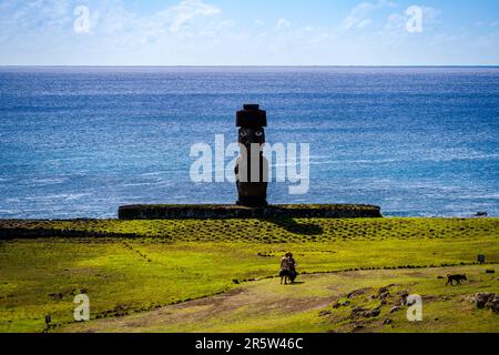 Osterinsel, Chile -- 25. Januar 2023.. Foto einer nach innen gerichteten Moai-Statue; zwei weibliche Touristen stehen in der Nähe der Stange und ein Hund ist in der Nähe. Stockfoto