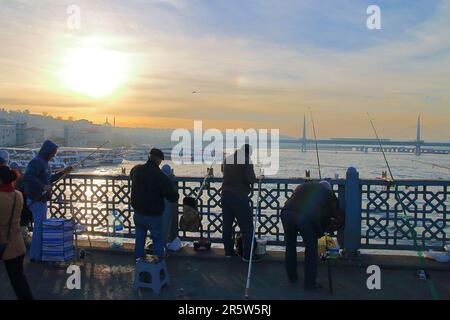 Das Foto wurde in Istanbul auf der Galata-Brücke gemacht. Auf dem Bild sind Fischer, die gegen die untergehende Sonne fischen. Stockfoto