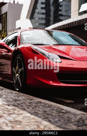 Ein vertikales Bild eines roten Ferrari 458 in der Farbe Rosso Corsa an einem Regentag Stockfoto