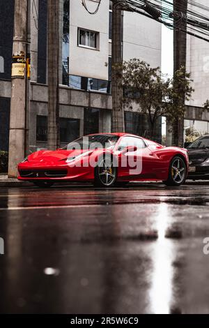 Ein vertikales Bild eines roten Ferrari 458 in der Farbe Rosso Corsa an einem Regentag Stockfoto