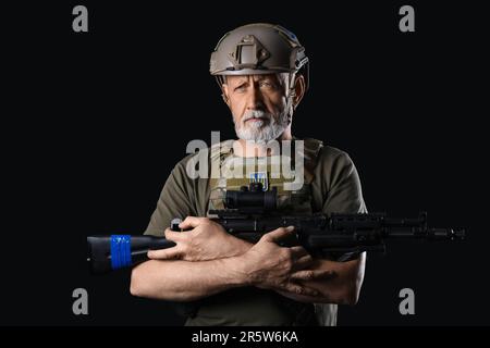 Ukrainischer Soldat mit Sturmgewehr auf dunklem Hintergrund Stockfoto