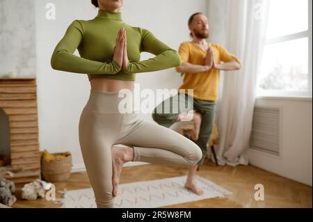 Ein Paar, das in Yoga-Vrikshasana-Baumhaltung steht, abgeschnitten mit selektivem Fokus Stockfoto