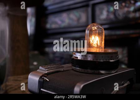 Eine Glühbirne auf einem alten Kameraobjektiv. Stockfoto