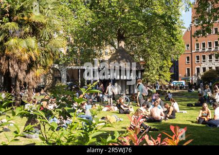 Menschen Sonnenbaden und Tudorbethan Holz gerahmt Market Cross Gebäude in Soho Square Gardens, Soho Square, Soho, London, W1, England, Großbritannien Stockfoto