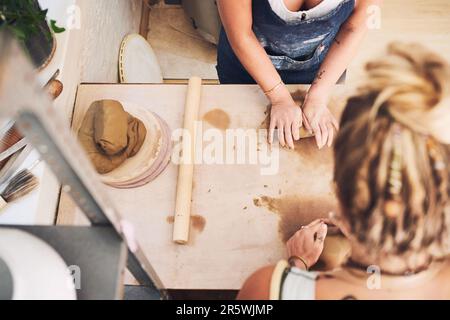 Sie wurden zum Erstellen von erstellt. Zwei unerkennbare Frauen kneten Ton in einem Töpferstudio. Stockfoto