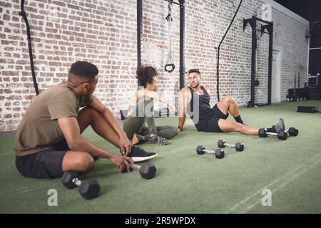 Treffen Sie bessere Entscheidungen, bessere Freunde. Eine Fitnessgruppe, die sich nach dem Training mit Kurzhanteln ausruht. Stockfoto