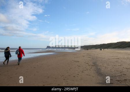 Saltburn Beach, North Yorkshire, 2. Januar 2022 mit Wanderer und Paddelboardern, die dem kühlen Wetter am Strand und am Pier trotzen Stockfoto