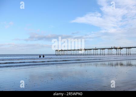 Saltburn Beach, North Yorkshire, 2. Januar 2022 mit Wanderer und Paddelboardern, die dem kühlen Wetter am Strand und am Pier trotzen Stockfoto