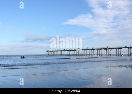 Saltburn Beach, North Yorkshire, 2. Januar 2022 mit Wanderer und Paddelboardern, die dem kühlen Wetter am Strand und am Pier trotzen Stockfoto