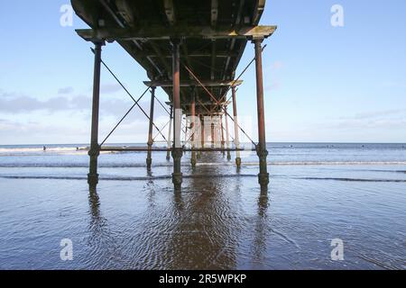 Saltburn Beach, North Yorkshire, 2. Januar 2022 mit Wanderer und Paddelboardern, die dem kühlen Wetter am Strand und am Pier trotzen Stockfoto