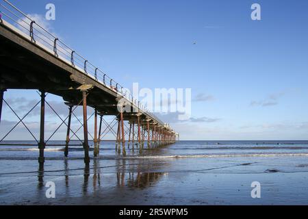 Saltburn Beach, North Yorkshire, 2. Januar 2022 mit Wanderer und Paddelboardern, die dem kühlen Wetter am Strand und am Pier trotzen Stockfoto