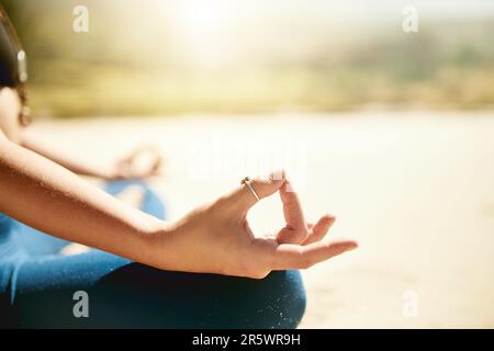 Lass los und befreie dich. Eine unbekannte Frau, die am Strand Yoga praktiziert. Stockfoto