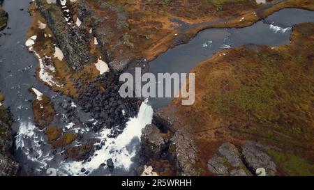 Drohnenaufnahme des nordischen islands Wasserfalls, massiver Wasserstrom, der von den Klippen hinunterfließt und eine wunderschöne Oxarafoss-Kaskade bildet. Isländische Natur und kalter Fluss. Zeitlupe. Stockfoto