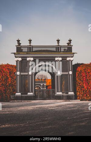 Herbstszene eines kunstvoll verzierten goldenen Torbogens in einem Garten in Wien Stockfoto