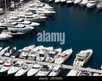 Ein lebendiger Blick aus der Vogelperspektive auf einen Hafen mit einer Flotte von Booten, die in den ruhigen Gewässern vor Anker liegen, und einem großen Gebäude auf einer Seite Stockfoto