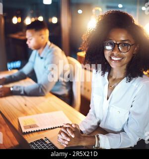Harte Arbeit ist für alle in diesem Büro selbstverständlich. Porträt einer jungen Geschäftsfrau, die nachts mit ihrem Kollegen in einem Büro arbeitet. Stockfoto