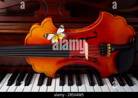 Farbenfroher Schmetterling auf barocker Violin auf Pian Keys Stilleben Stockfoto