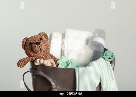 Mutters Tasche mit Babysachen auf hellgrauem Hintergrund Stockfoto