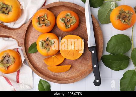 Köstliche reife Persimonen und Messer auf weißem Tisch, flach liegend Stockfoto