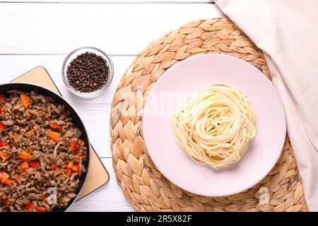 Köstliche Spaghetti, Hackfleisch mit Karotten und Pfeffer auf einem weißen Holztisch, flach liegend Stockfoto