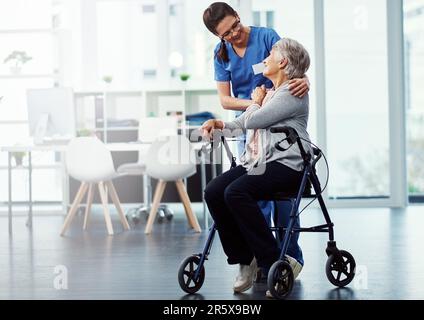 Sie gibt ihren Patienten 100. Vollbild einer jungen Krankenschwester, die mit ihrem Seniorenpatienten im Altersheim spricht. Stockfoto