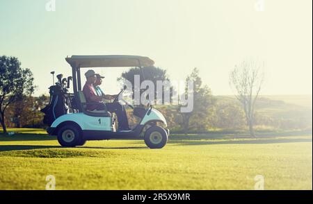 Der Klubbin ist weg. Zwei Golfer, die in einem Wagen auf einem Golfplatz reiten. Stockfoto