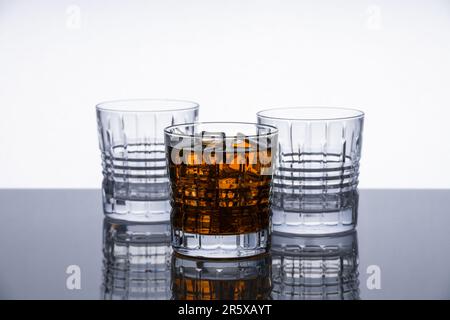 Whiskey-Gläser aus Kristall auf einer reflektierenden Oberfläche. Isoliertes Objekt. Dramatischer moderner Hintergrund. Modernes Design. Stockfoto
