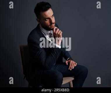 Sein Verstand ist im Profitmodus. Studioaufnahme eines stilvollen jungen Geschäftsmanns, der aufmerksam aussieht, vor grauem Hintergrund. Stockfoto