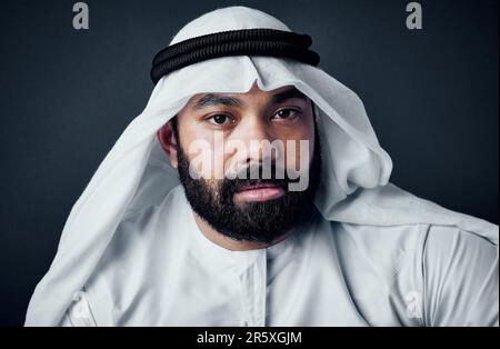 Der traditionelle Geschäftsmann. Studiofoto eines jungen Mannes in islamischer traditioneller Kleidung, der vor einem dunklen Hintergrund posiert. Stockfoto