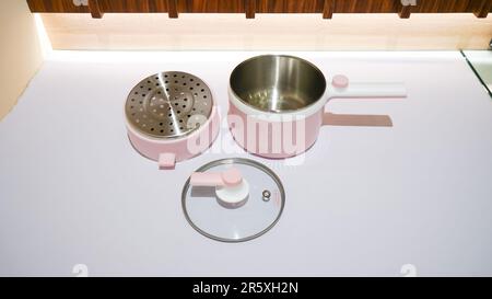 Ein eleganter rosafarbener elektrischer Dampfgarer ist ein Küchengerät, das Dampf verwendet, um Lebensmittel schnell und effizient zu kochen. Stockfoto