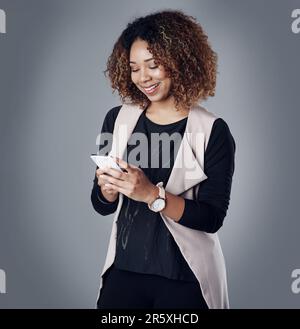 Das intelligente Gerät, das alles kann. Studiofoto einer jungen Geschäftsfrau, die ein Telefon vor grauem Hintergrund benutzt. Stockfoto
