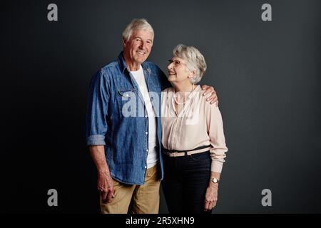 Sie ist mein "glücklich bis ans Lebensende". Studioporträt eines liebevollen Seniorenpaares, das vor grauem Hintergrund posiert. Stockfoto
