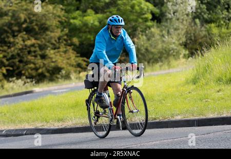 Stony Stratford, Großbritannien - Juni 4. 2023: Älterer Mann fährt Fahrrad auf einer englischen Landstraße. Stockfoto