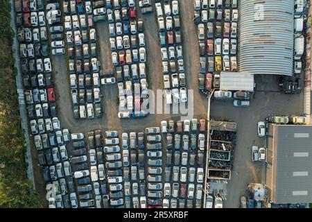 Luftaufnahme des großen Parkplatzes von Schrottplatz mit Reihen von weggeworfenen gebrochenen Autos. Recycling von Altfahrzeugen Stockfoto