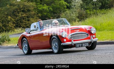 Stony Stratford, Großbritannien - 4. 2023. Juni: 1964 roter AUSTIN HEALEY 3000 Klassiker, der auf einer englischen Landstraße fährt. Stockfoto