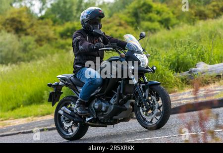 Stony Stratford, Großbritannien - 4. 2023. Juni: 2014 HONDA NC Motorrad, das auf einer englischen Landstraße fährt. Stockfoto