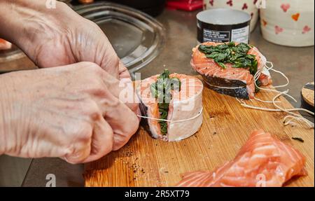 Der Küchenchef bereitet Lachs mit Spinat und gebackener Zitrone und Sauce zu. Französische Gourmetküche Stockfoto